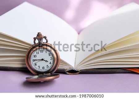 Watch in retro style with a blank notebook on pastel purple background