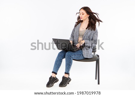 Woman is holding a laptop on her knees. Woman with developing hair and laptop. Girl on a white background works with a laptop. Freelance girl. Freelancer on white background. She put computer on lap