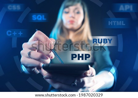 Programming Web site development. Girl chooses a programming language. Woman developer holds tablet in her hands. Web developer on a dark background. Website building. Website launch. PHP. SQL. RUBY