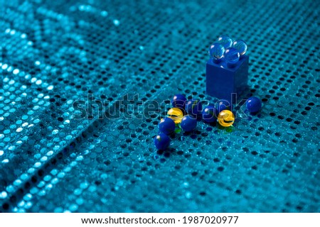A closeup shot of marbles on blue sequin fabric
