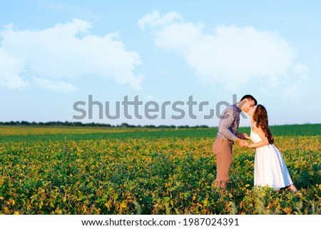 Young romantic wedding couple are posing on grass field. Happy loveling woman and man are walking together at beautiful nature on summer day. Love story concept. Template for invitation, greeting card