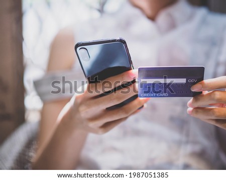 Young woman is holding credit card and smart phone to buy product online from the website on internet, e-commerce and online shopping, financial transaction