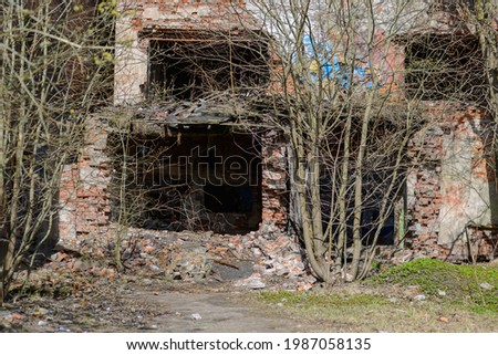 Grim photo of an old dilapidated brick building with collapsed ceilings. The floor inside the building and the ground around it are littered with broken bricks. Selective focus