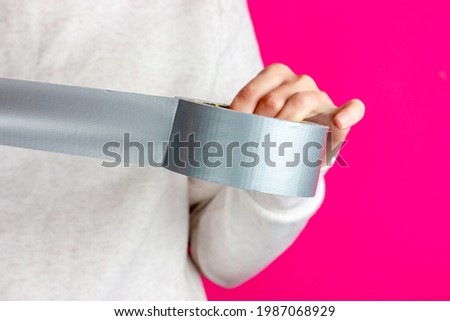 Roll of sticky tape in hands. Packing the parcel with adhesive tape. Tearing off the adhesive tape. Roll of duct tape. Royalty-Free Stock Photo #1987068929