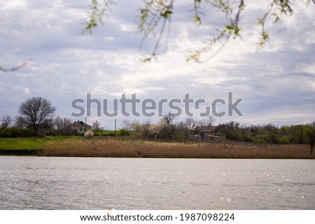 rural landscape. lake, reeds, farmhouse on a hill
