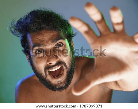 young man angry face indicating hand to you studio shot
