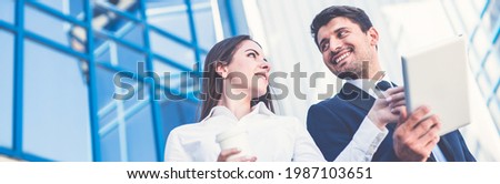 The happy man and woman stand with a tablet on the background of the building