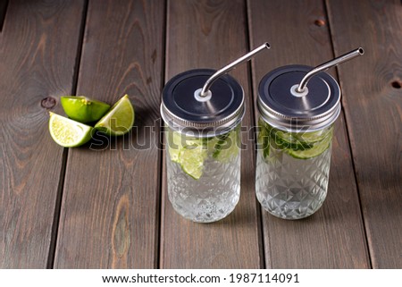 Summer refreshing drinks. Citrus non-alcoholic refreshing chilled drinks in glass bottles with lids and metal cocktail tubes on a wooden background.