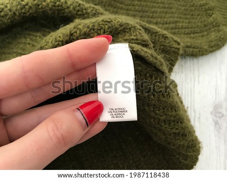 White tag with fabric composition closeup on green sweater