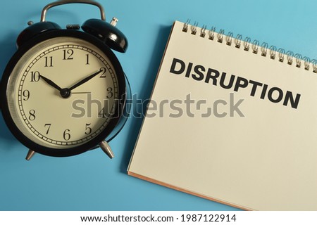 Top view of clock and notebook written with DISRUPTION
