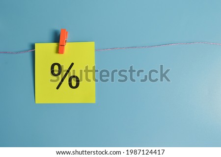 Paper note hanging on a rope with percent icon isolated on blue background