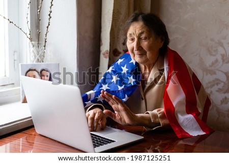 Independence Day celebration after quarantine. Granny looking at laptop screen and celebrating national holiday with her family online, care about senior people, personal technology, focus on woman