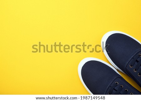 Blue pair of sneakers gym shoes on a yellow background. View from above. 