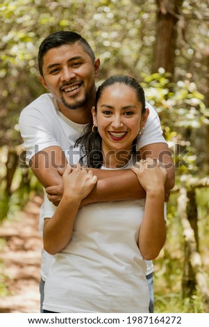Hispanic couple in love hugging in the park - man hugging his wife in the middle of nature - Latin couple