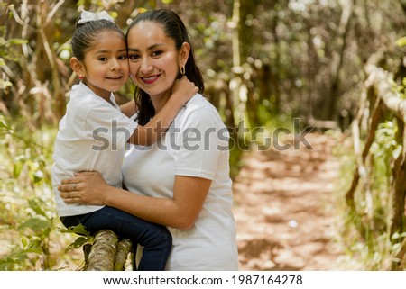 Portrait of hispanic mom hugging her daughter in the park-loving mother and daughter-happy family taking a walk