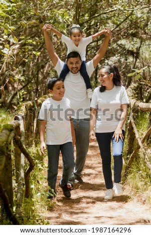 Happy hispanic family walking in the natural park - young parents with their children in the park -latin family Royalty-Free Stock Photo #1987164296