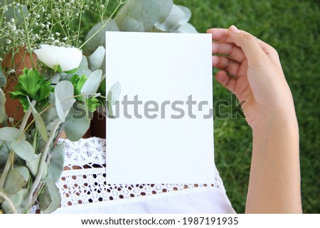 Girl wedding or birthday greeting card mock up scene with woman's hand in holding blank a5 paper card and eucalyptus. Empty space. Picture for blog or social media.