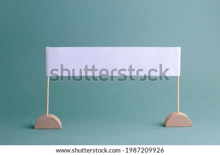 Blank advertising poster on wooden stands on a turquoise background. Mock-up for an ad, promotional message, invitation, or other text.