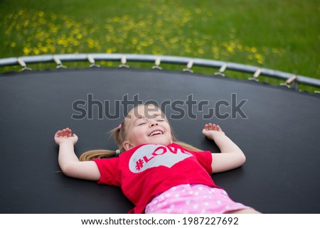baby girl lying on a trampoline, tired after active games, homestead