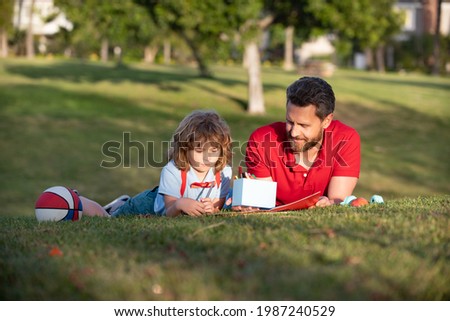 happy fathers day. happy family. dad and kid boy relax on grass in park. child hold learning to draw