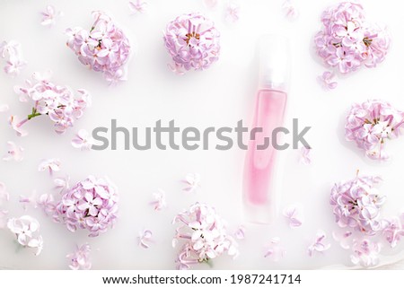 Pink perfume bottle and lilac branch on a white background. The concept of advertising perfumes. A bottle of perfume without text. Floral aromatherapy layout . Copy space