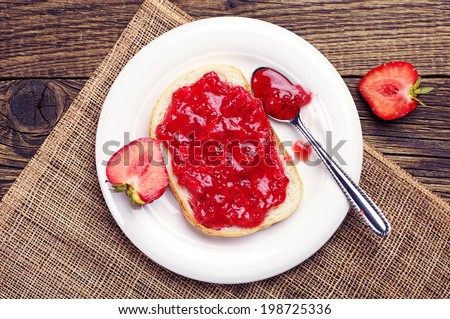 Top view on bread with strawberry jam on wooden table Royalty-Free Stock Photo #198725336