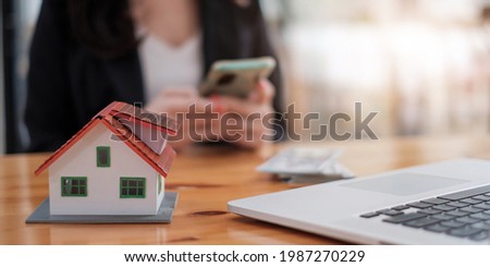 Real estate agent with house model hand putting signing contract,have a contract in place to protect it,signing of modest agreements form in office.Concept real estate,moving home or renting property
