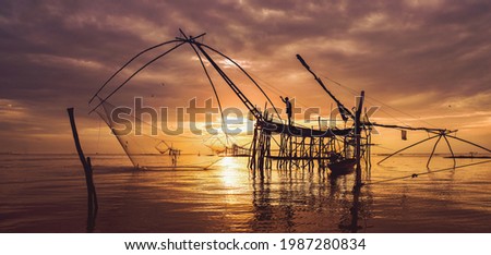 silhouette scenery of sunrise over lake with thai traditional fishing trap at Pakpra, phatthalung province thailand