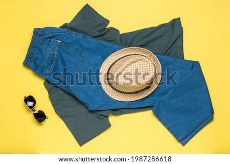 Sunglasses and men's summer clothing on a yellow background. Flat lay. Summer holidays and travel.