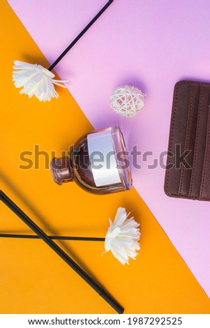 50 ml Perfume bottle with blank white label and flower and wallet on orange-pink background. Perfume bottle stock photo