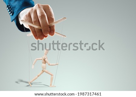 Male hand, puppeteer controls the puppet puppet with strings. A doll on her knees. The concept of world conspiracy, world government, manipulation, control Royalty-Free Stock Photo #1987317461
