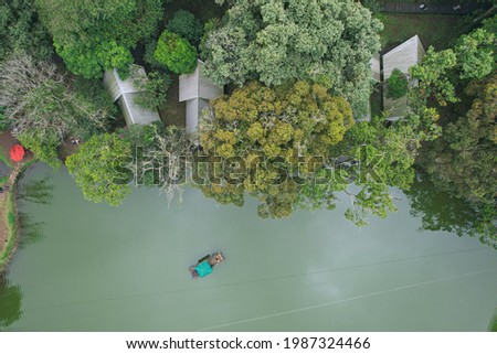 Top view of "danau 2 warna" or 2 colos lake with green scenery, bamboo boat and some houses on the bank of the lake with tropical forest background. Puncak, West Java, Indonesia. June, 2021.