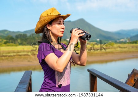 A young tourist looking at birds with spyglasses from the wooden piers of the Urdaibai marshes, a biosphere reserve in Bizkaia next to Mundaka. Basque Country