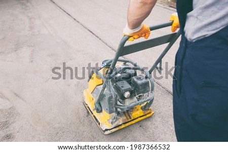 The worker tamping a gravel by the vibration plate Royalty-Free Stock Photo #1987366532