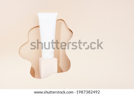 Product photography with props. White cosmetic tube on light color background. Minimal concept.