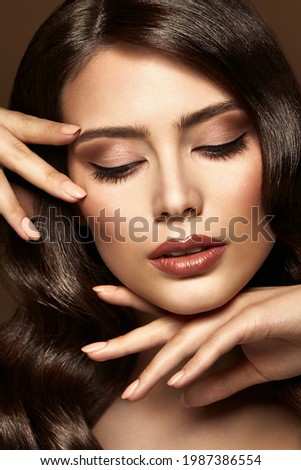 Woman Make up Portrait. Professional Face Cosmetic Care and Nail Manicure. Beauty Model Girl with Closed Eyes Showing Eye Shadow and Lips Makeup over Brown Background Royalty-Free Stock Photo #1987386554