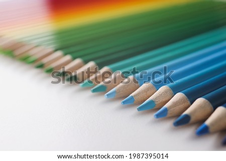 Many multi-colored pencils lying in colors of rainbow on white background