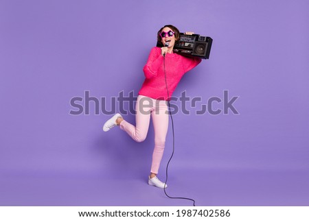Full length photo of young girl happy smile sing microphone hold boombox party wear pants isolated over violet color background