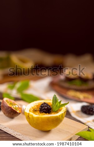 Dark moody food photography closeup of a maracuya passion fruit with blackberries. Natural and healthy food concept.