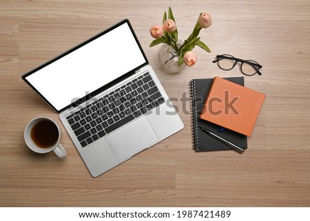 Overhead shot of laptop computer, notebook and coffee cup on wooden background.