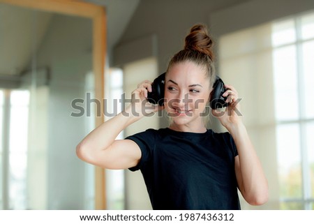 Beautiful Caucasian woman Athletic Sports wearing wireless Headphones Listens to Podcast or Sport Music Playlist while Running on Treadmill. Energetic Female Athlete Training in Gym Alone.