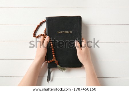 Female hands with Holy Bible on white wooden background