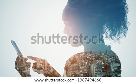 Silhouette of woman using a smart phone and modern cityscape. Double exposure.