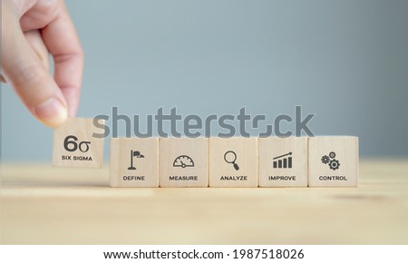 Hand pick up Six sigma icon on wooden cubes  standing on wood table with blue background, clean tone. The DMAIC Industrial technology quality control, industrial process improving and lean concept.