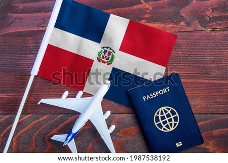 Flag of Dominican Republic with passport and toy airplane on wooden background. Flight travel concept 