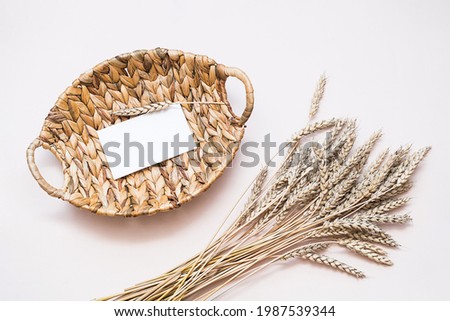 Eco-style stationery still life. Mockup business card, invitation, natural eco materials, . Ears of wheat and rattan basket on the light table. top view.
