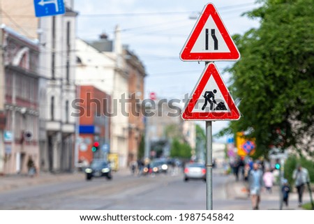 warning signs about street repairs on a blurred urban background, close-up