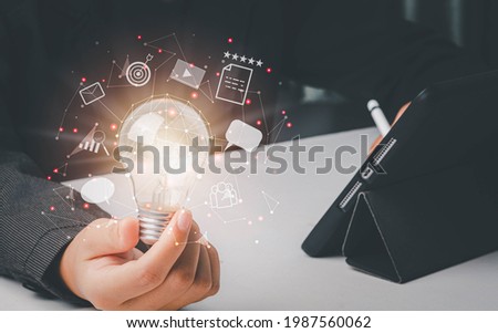Content marketing concept. Businessman holding light bulb of creative idea and usering tablet research best content for marketing plan. Conneting line of communication icon.  Royalty-Free Stock Photo #1987560062