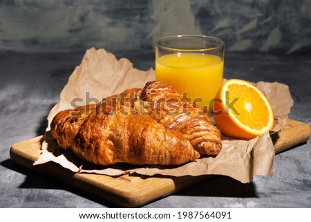 glass of orange juice and two croissants on wrapping paper. Close-up.