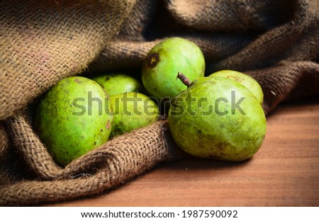Ripe mangoes falling from sack on wooden table. Also known as Manga in Malayalam.
